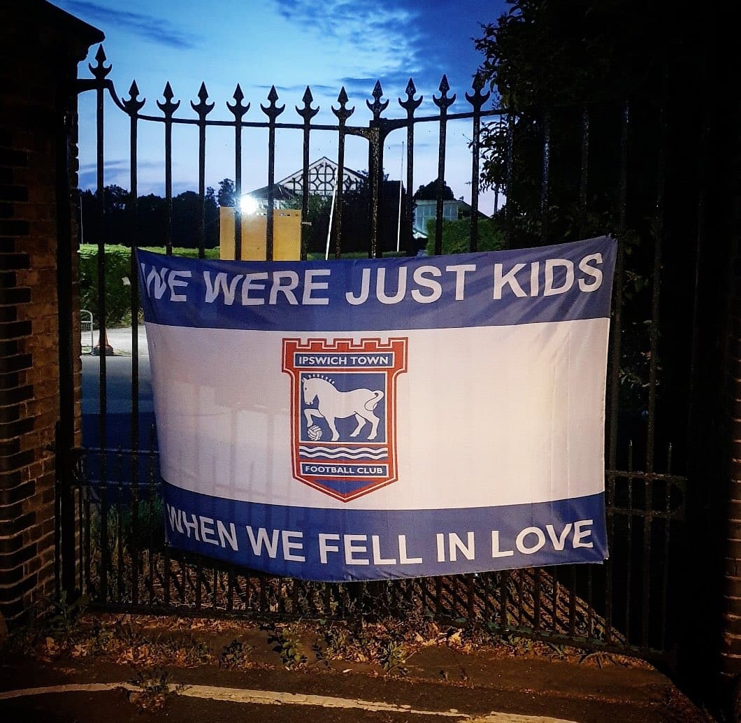 Supporters holding a finished custom football flag at a match
