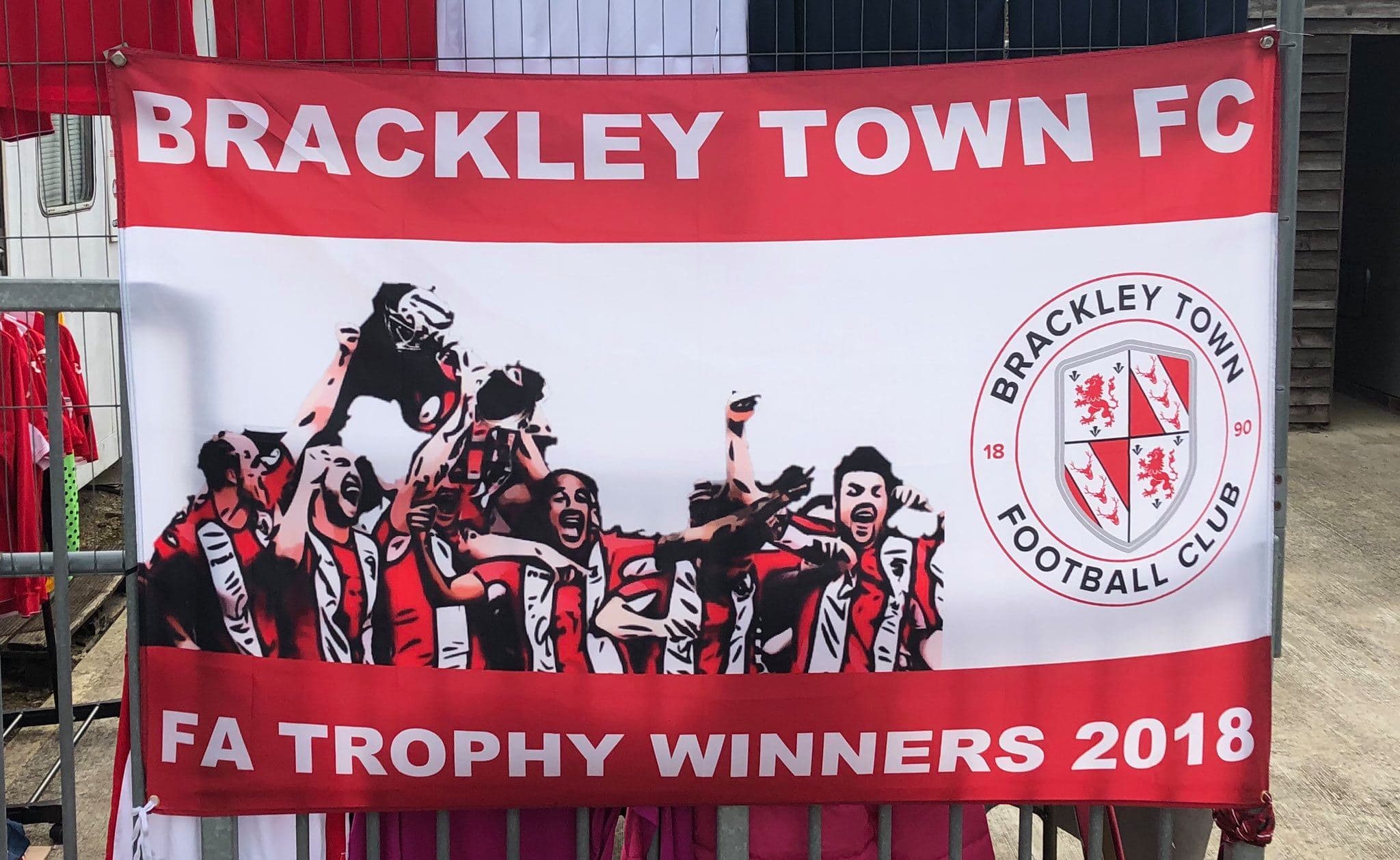 A finished custom supporter flag displayed beside a football pitch