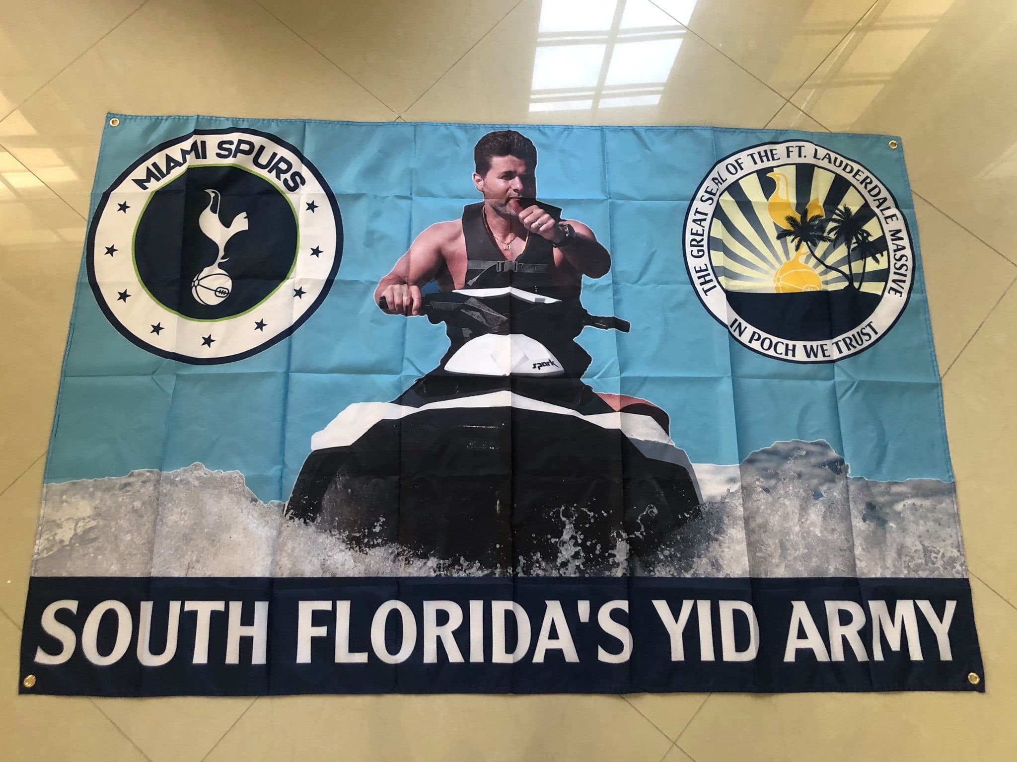 A large portrait-led football tribute flag held by supporters